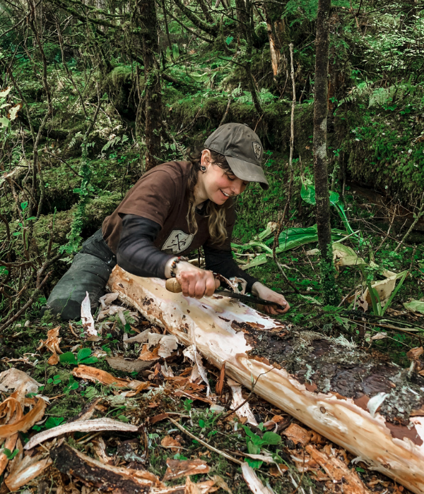 Crew leader Jesse peels bark off of a log that will be used in trail construction.