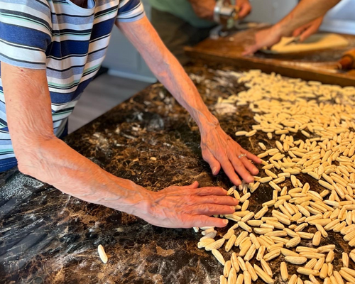 A woman kneads pasta dough on a kitchen counter