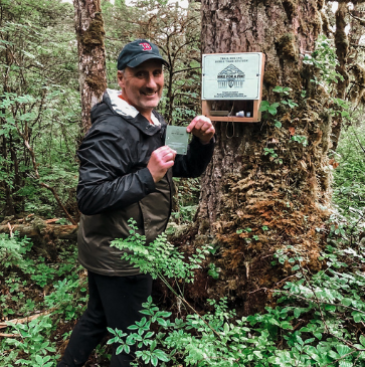 Photo of board president Mark Pusich checking off his Hike for a Pint passport on the Horse Tram trail.